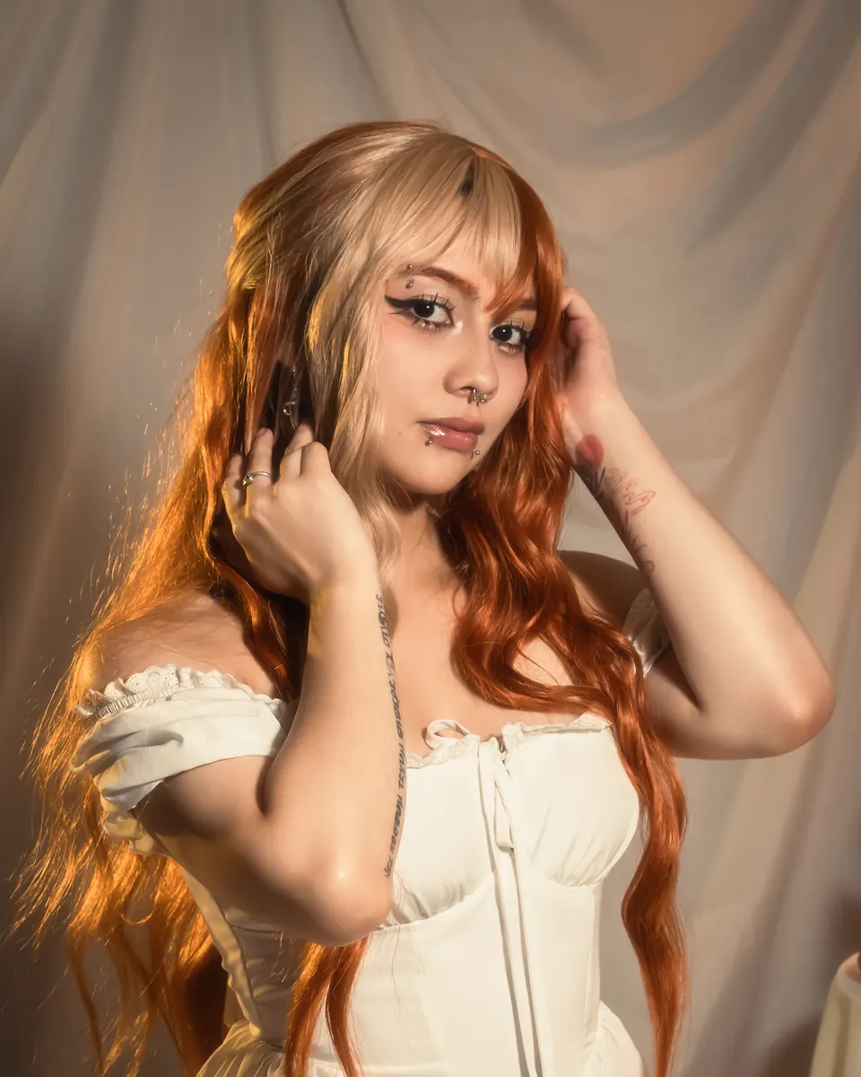 Modelo con vestido blanco frente a cortina crema y lámpara cálida